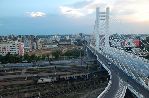 Train passing under modern suspension bridge in Bucharest free photo
